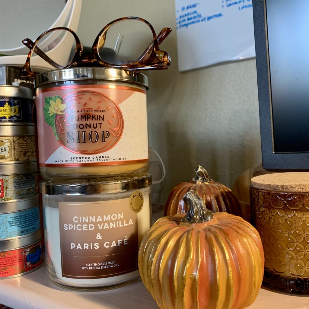 Glasses on two three-wick candles next to pumpkin