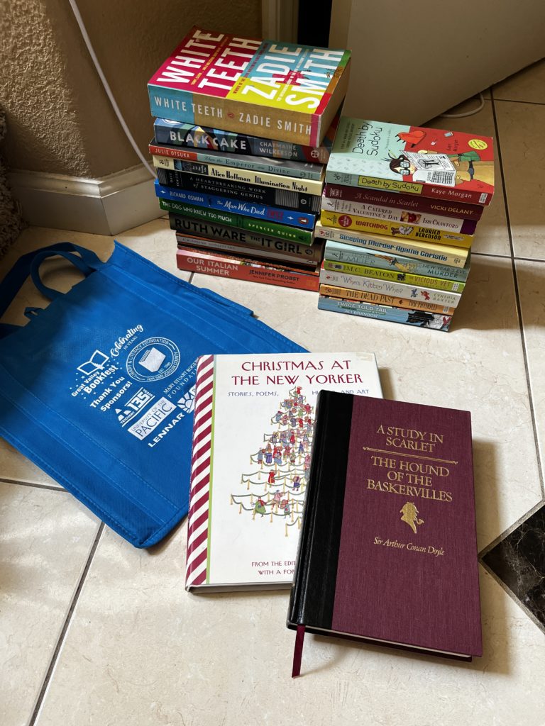 Stacks of books next to a blue bag (left) and two books in the front